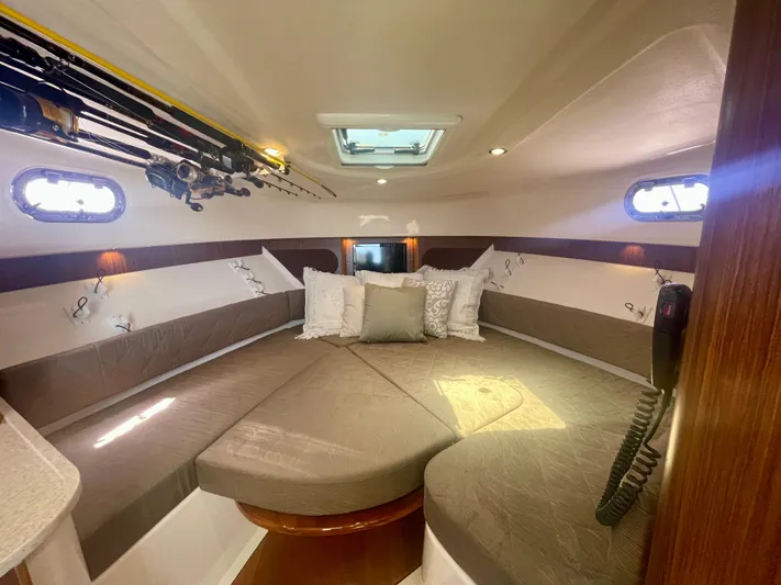 Hobi One Yacht Photos Pics 2015 Pursuit 345 Offshore cabin interior with cozy seating and fishing rods.