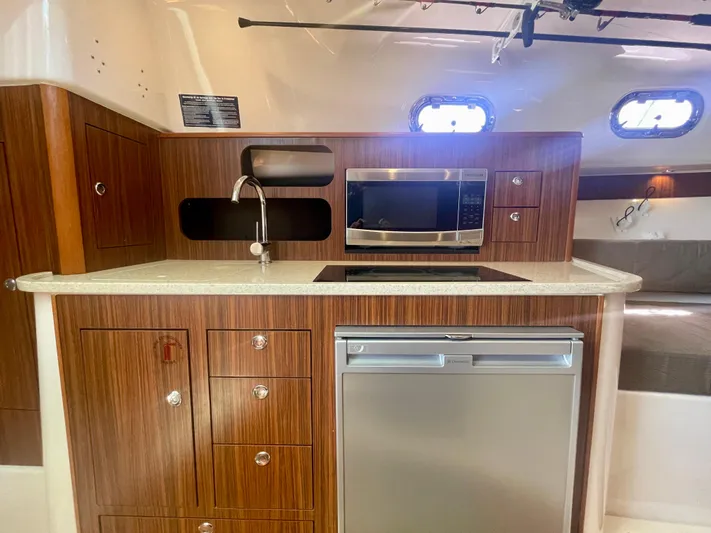 Hobi One Yacht Photos Pics 2015 Pursuit 345 Offshore yacht kitchen with wood cabinetry, microwave, sink, and refrigerator.