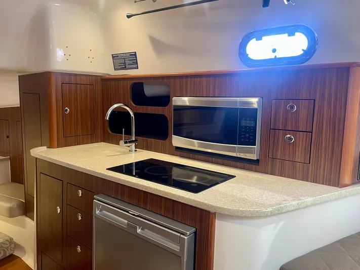 Hobi One Yacht Photos Pics 2015 Pursuit 345 Offshore yacht kitchen with wood cabinets, microwave, and sink.