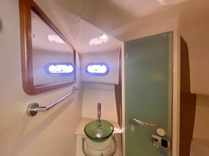 Hobi One Yacht Photos Pics 2015 Pursuit 345 Offshore bathroom with glass sink, mirror, and porthole windows.
