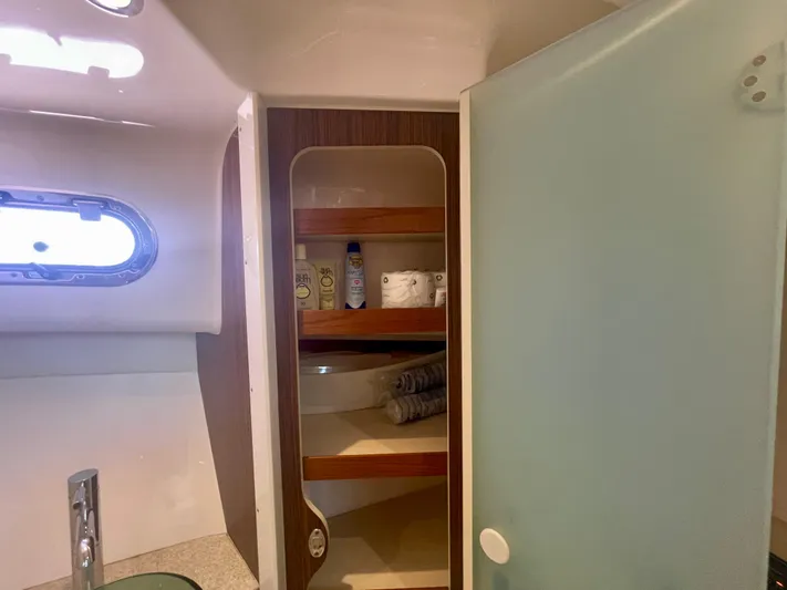 Hobi One Yacht Photos Pics 2015 Pursuit 345 Offshore bathroom with shelves, toiletries, and a frosted glass door.