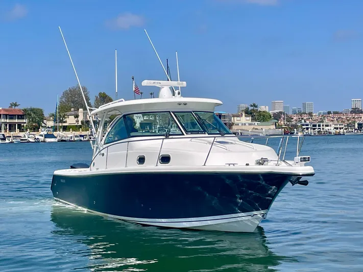 Hobi One Yacht Photos Pics 2015 Pursuit 345 Offshore boat cruising in a scenic harbor setting.