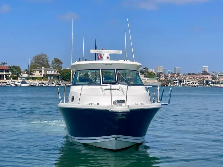 Hobi One Yacht Photos Pics 2015 Pursuit 345 Offshore boat on calm water with cityscape background.