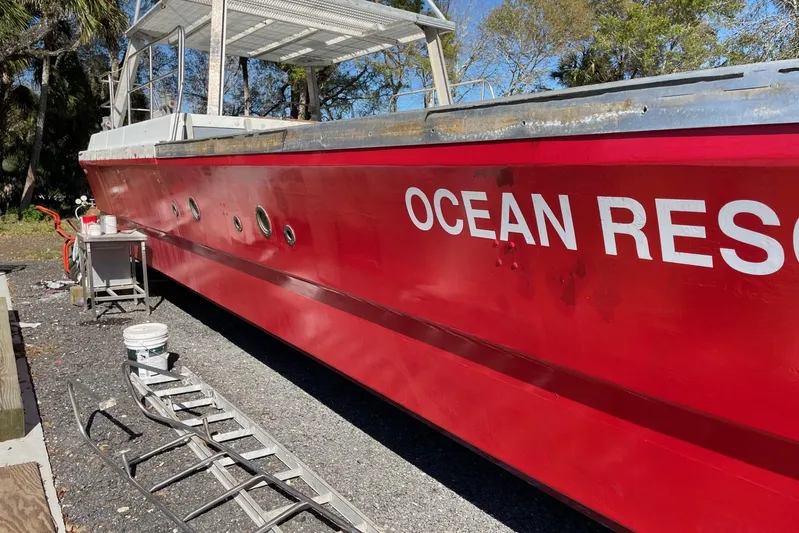 Asi Tender Yacht Photos Pics Red 1987 Commercial Buoy Tender "Ocean Res" on land, with maintenance equipment nearby.
