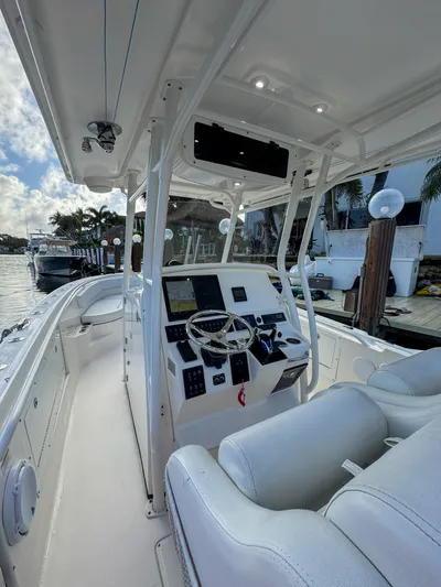  Yacht Photos Pics 2013 Edgewater 318CC boat interior with steering console and seating, docked by the water.