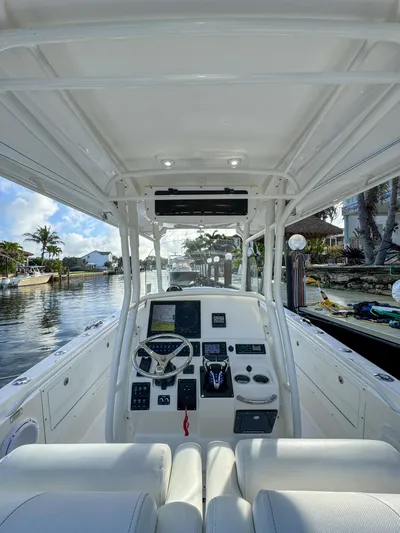  Yacht Photos Pics 2013 Edgewater 318CC boat interior with steering console, docked by a scenic waterfront.