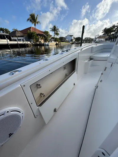  Yacht Photos Pics 2013 Edgewater 318CC boat interior with storage compartment, docked by a scenic waterfront.