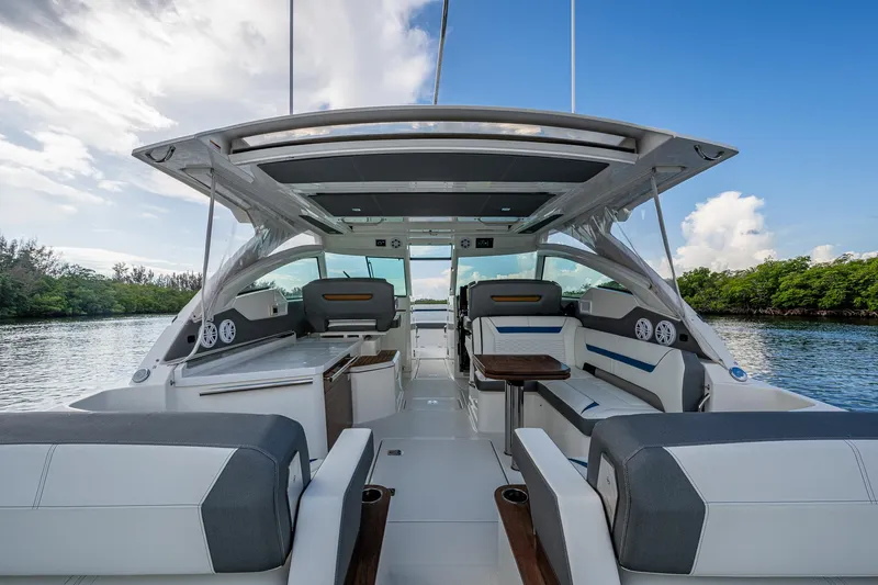  Yacht Photos Pics 2021 Tiara Yachts 38 LX interior with seating, table, and canopy on a calm waterway.