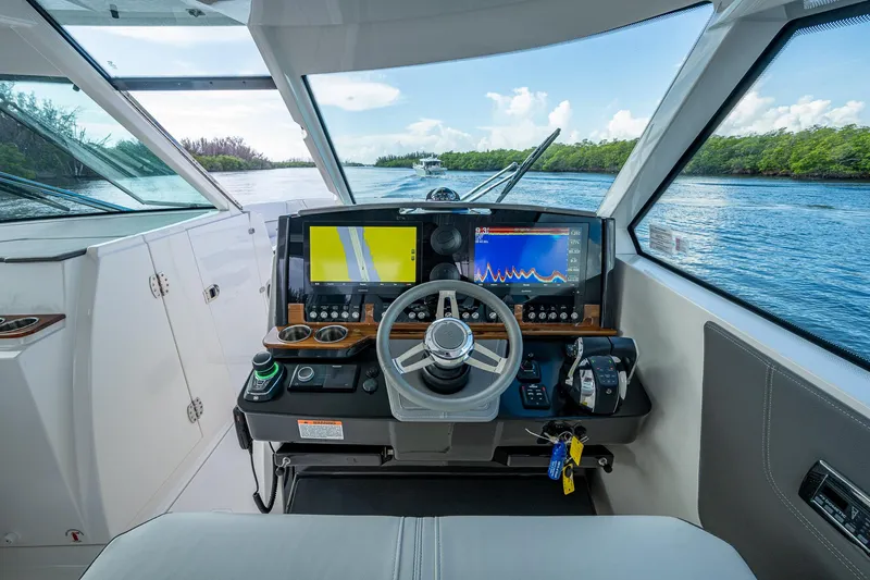  Yacht Photos Pics 2021 Tiara Yachts 38 LX helm with navigation screens and steering wheel on a scenic waterway.