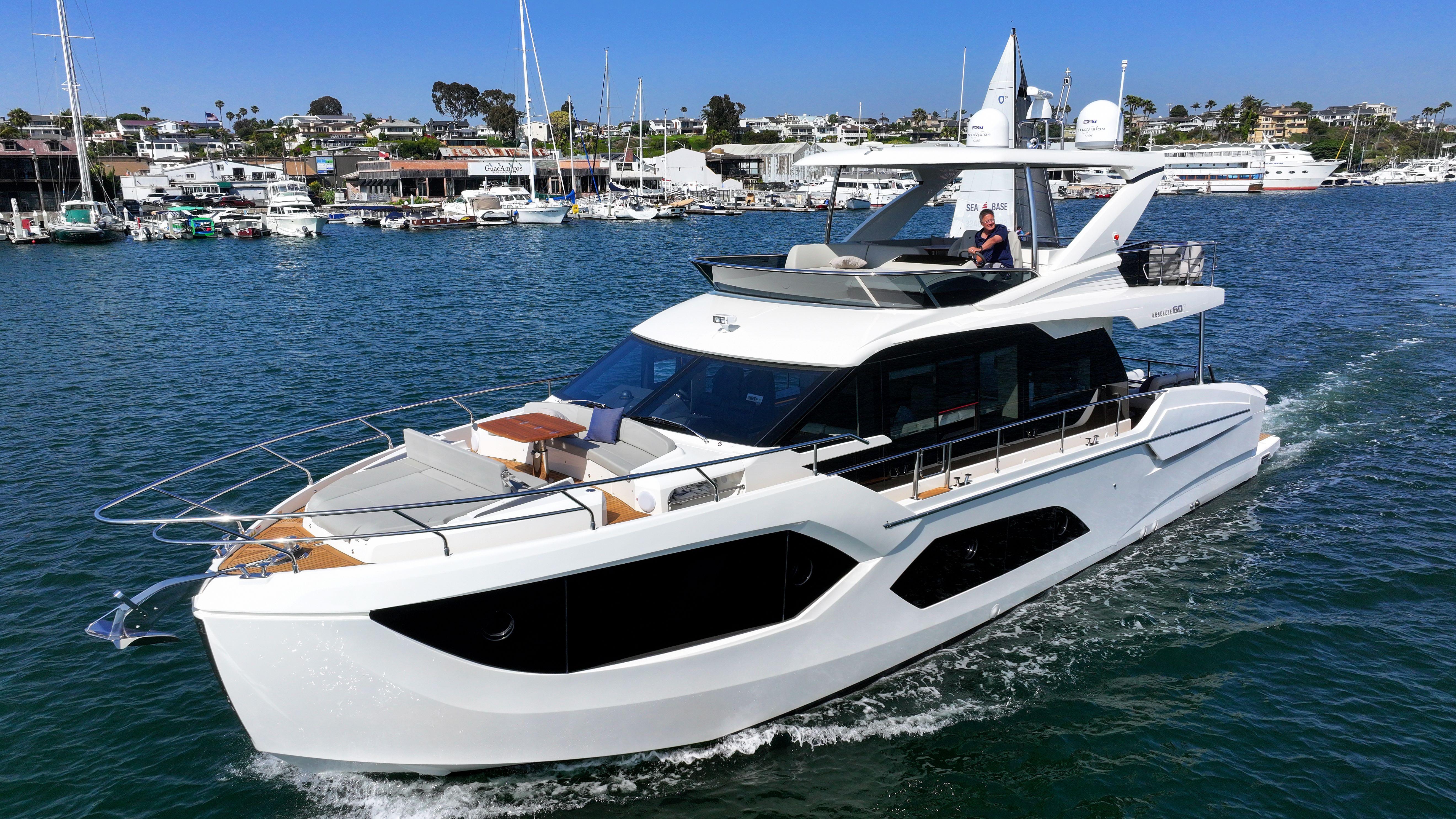 2024 Absolute 60 Fly Co Ownership yacht cruising in a marina, showcasing sleek design and luxury.