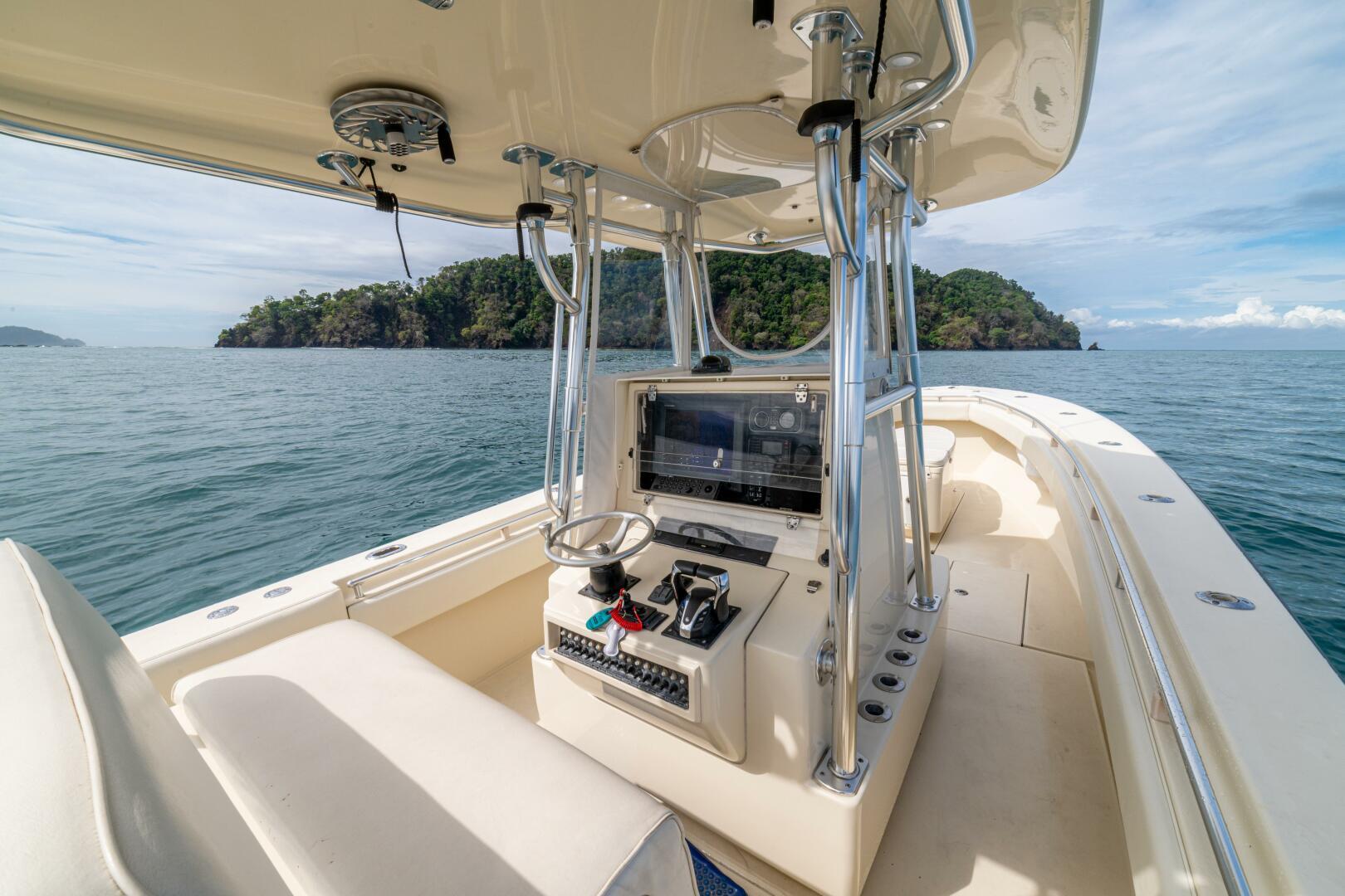 2007 Contender 33 boat interior with steering console, on calm sea near lush island.