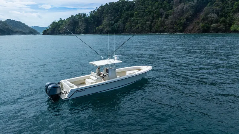 D Flawless Yacht Photos Pics 2007 Contender 33 boat on calm water near lush, forested coastline.