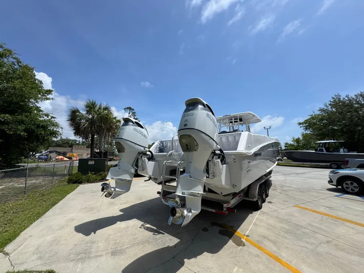  Yacht Photos Pics 2022 Twin Vee 340 GFX CC boat with dual outboard engines in a sunny parking lot.