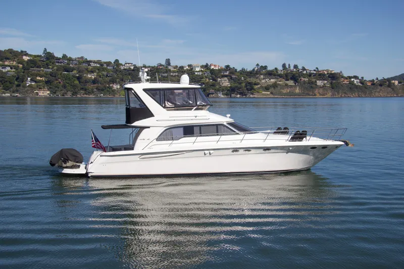 Eclipse Yacht Photos Pics 1998 Sea Ray 480 Sedan Bridge yacht on calm water with scenic hillside background.