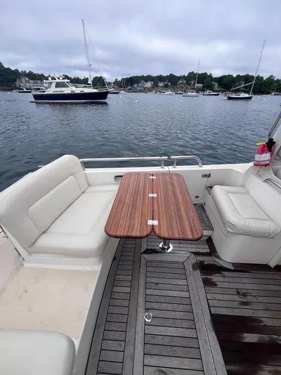 Barbican V Yacht Photos Pics 2014 MJM 36z Downeast boat with teak table and seating, docked in a scenic harbor.