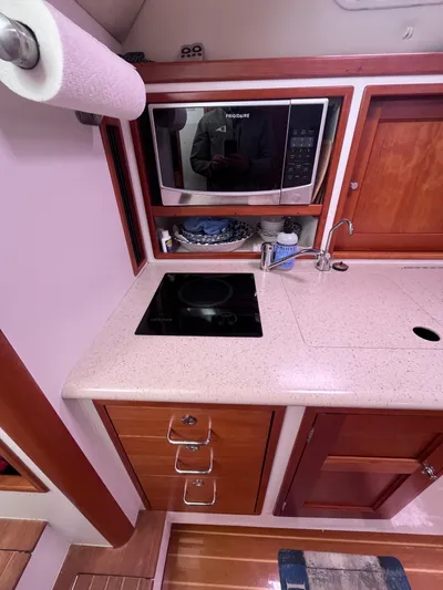 Barbican V Yacht Photos Pics 2014 MJM 36z Downeast boat kitchen with microwave, stove, and wooden cabinetry.