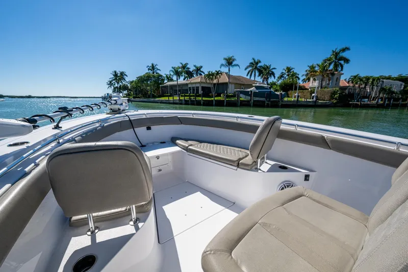  Yacht Photos Pics 2023 Sportsman Open 302 Center Console boat interior with seating, on a sunny waterfront.