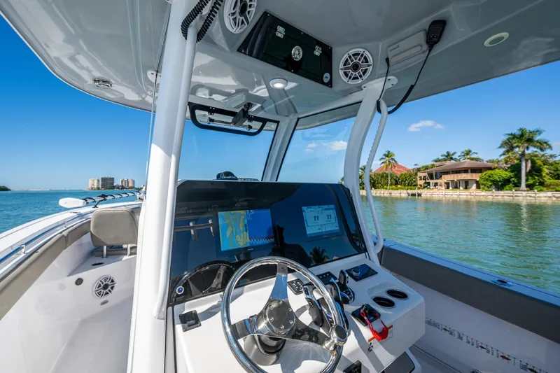  Yacht Photos Pics 2023 Sportsman Open 302 Center Console boat interior with navigation system, steering wheel, and waterfront view.
