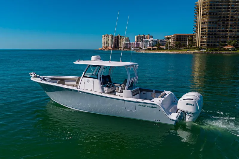  Yacht Photos Pics 2023 Sportsman Open 302 Center Console boat cruising near coastal cityscape.