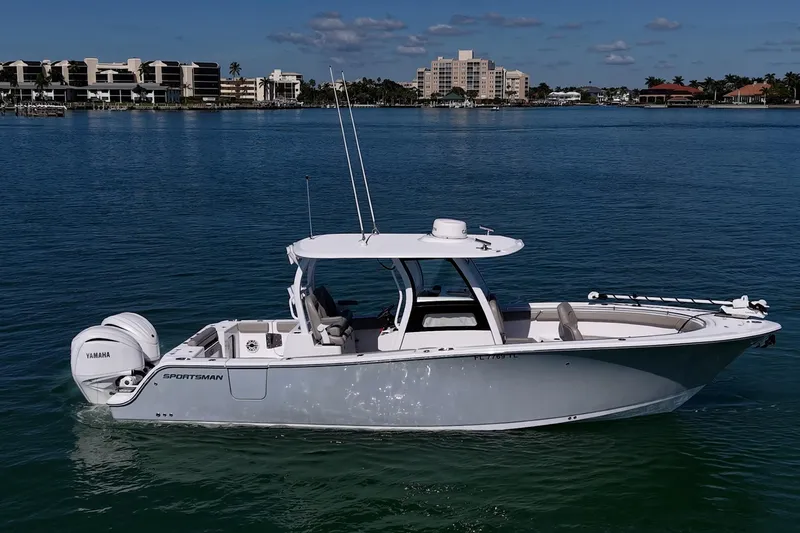  Yacht Photos Pics 2023 Sportsman Open 302 Center Console boat on calm water, cityscape background.