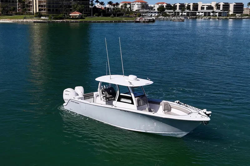  Yacht Photos Pics 2023 Sportsman Open 302 Center Console boat on calm water near coastal buildings.