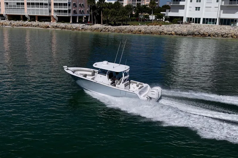  Yacht Photos Pics 2023 Sportsman Open 302 Center Console cruising on calm waters near coastal buildings.