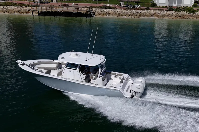 Yacht Photos Pics 2023 Sportsman Open 302 Center Console boat cruising on calm water near a dock.