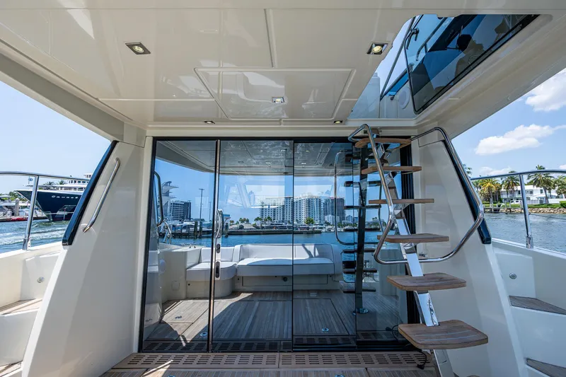 Blue B Yacht Photos Pics 2015 Beneteau MONTE CARLO yacht interior with glass doors and wooden steps, overlooking water.