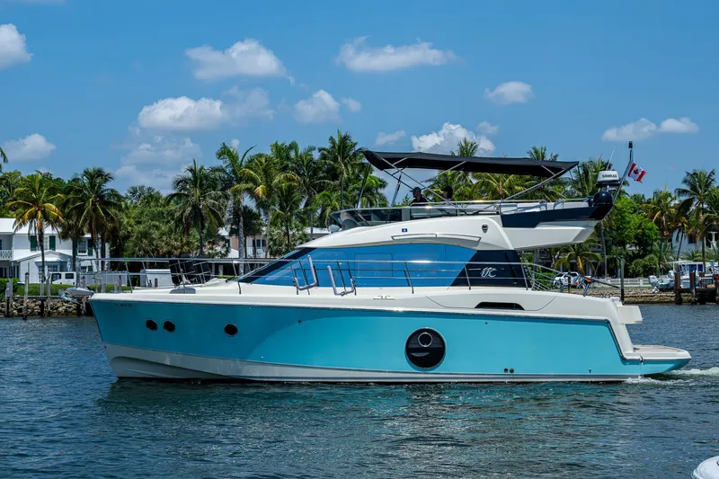 Blue B Yacht Photos Pics 2015 Beneteau Monte Carlo yacht cruising on a sunny day with palm trees in the background.
