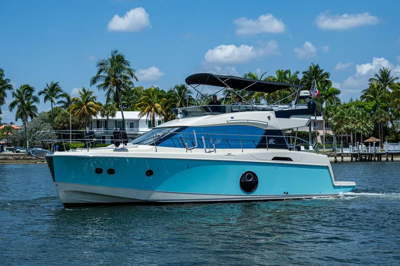 Blue B Yacht Photos Pics 2015 Beneteau Monte Carlo yacht cruising on a sunny day with palm trees in the background.