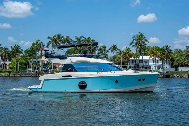 Blue B Yacht Photos Pics 2015 Beneteau Monte Carlo yacht cruising on a sunny day with palm trees in the background.