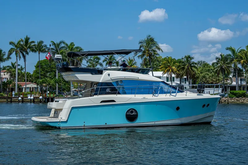 Blue B Yacht Photos Pics 2015 Beneteau Monte Carlo yacht cruising on a sunny day with palm trees in the background.