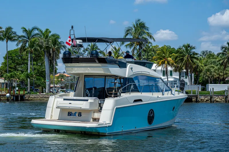 Blue B Yacht Photos Pics 2015 Beneteau MONTE CARLO yacht cruising on a sunny day with palm trees in the background.