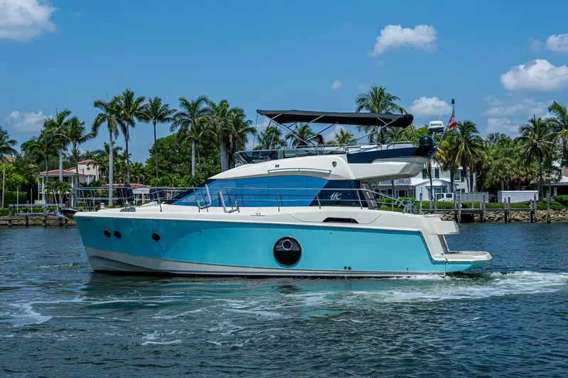 Blue B Yacht Photos Pics 2015 Beneteau Monte Carlo yacht cruising on a sunny day with palm trees in the background.