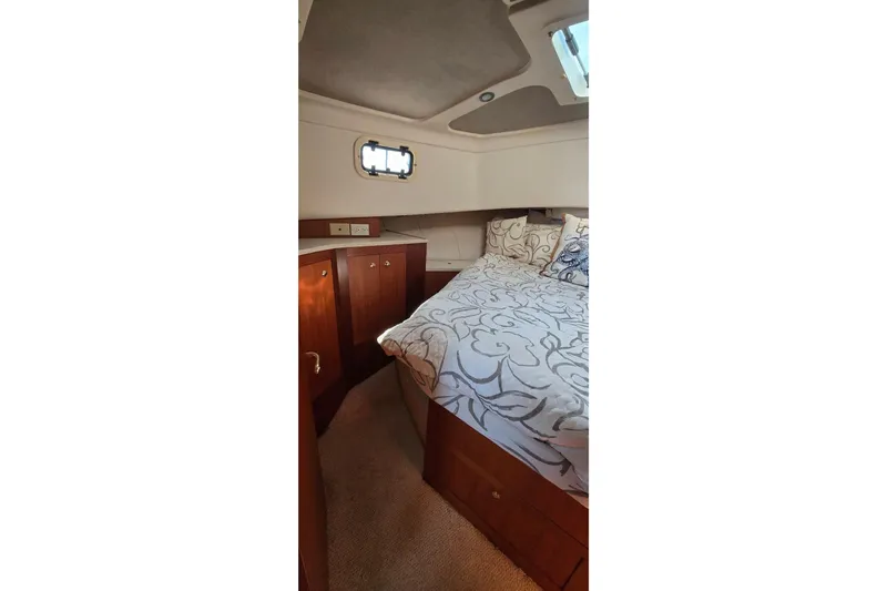 Polly Yacht Photos Pics Cozy cabin interior of 2000 Mainship 390 Trawler with elegant bedding and wooden cabinetry.