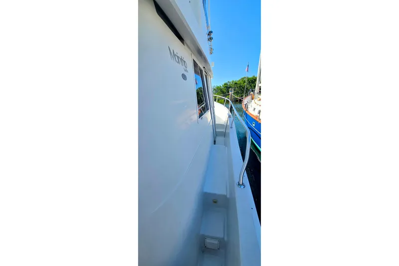 Polly Yacht Photos Pics 2000 Mainship 390 Trawler side view with railing, docked near other boats.