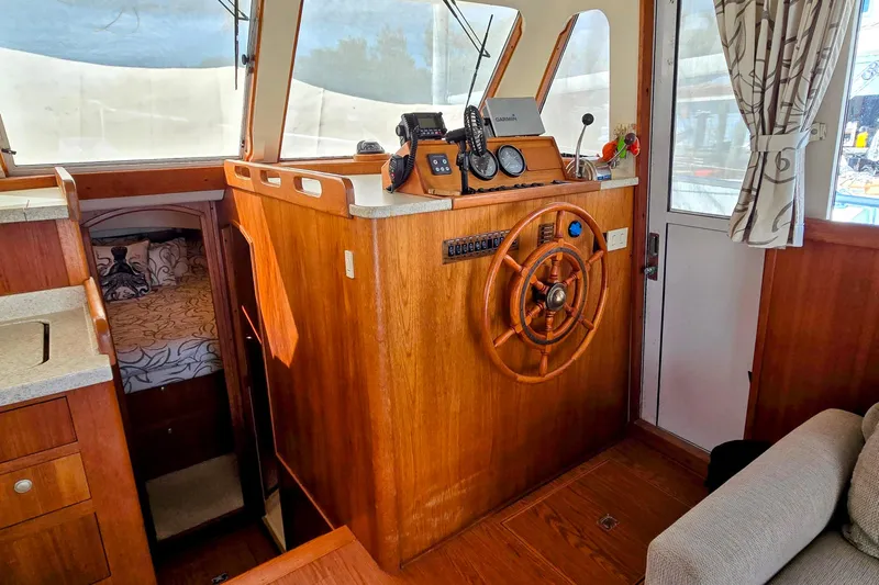 Polly Yacht Photos Pics 2000 Mainship 390 Trawler interior with wooden helm, navigation equipment, and cozy cabin.
