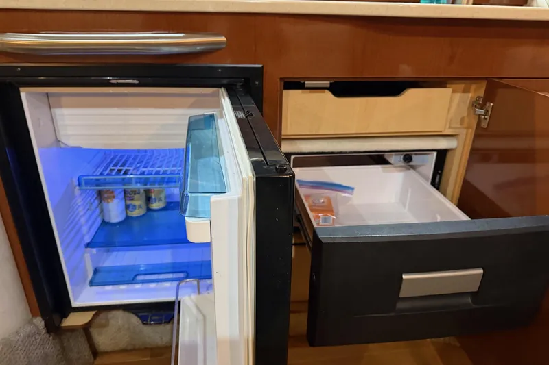 Finding Time Yacht Photos Pics Interior of 2011 Sea Ray 350 Sundancer with open fridge and drawer, showcasing storage space.