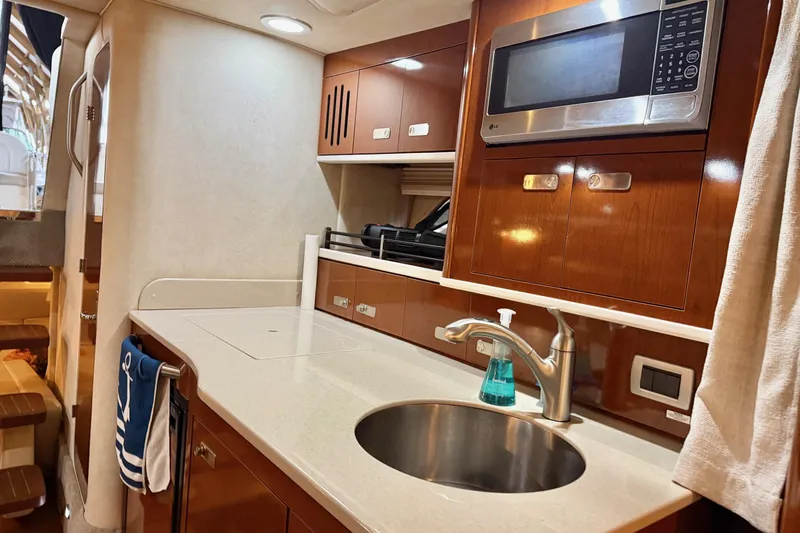 Finding Time Yacht Photos Pics 2011 Sea Ray 350 Sundancer yacht interior kitchen with sink, microwave, and wooden cabinetry.