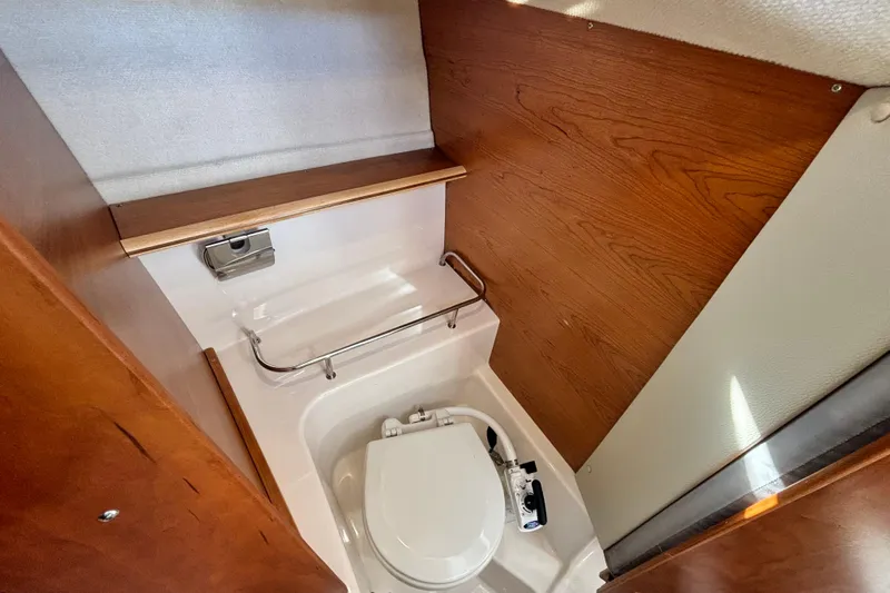  Yacht Photos Pics 2024 Cutwater C-248 Coupe boat interior with compact marine toilet and wooden paneling.
