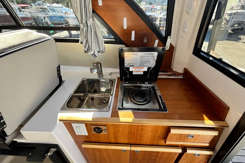  Yacht Photos Pics 2024 Cutwater C-248 Coupe interior kitchen with sink, stove, and wooden cabinetry.