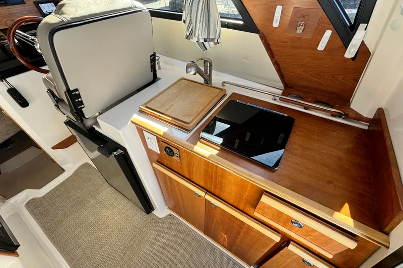  Yacht Photos Pics 2024 Cutwater C-248 Coupe interior with kitchenette, featuring wooden cabinetry and modern appliances.