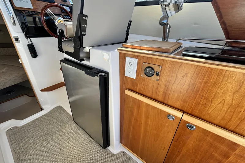  Yacht Photos Pics 2024 Cutwater C-248 Coupe interior with kitchenette, featuring wood cabinetry and stainless steel appliances.