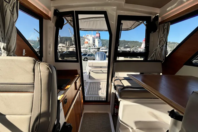  Yacht Photos Pics Interior view of 2024 Cutwater C-248 Coupe, showcasing seating and table with marina backdrop.