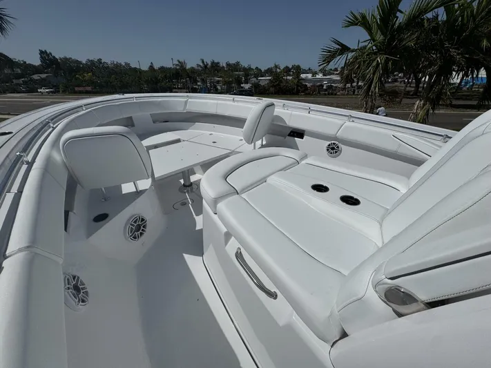  Yacht Photos Pics 2025 Sportsman 352 Open boat interior with white seating and table, surrounded by palm trees.