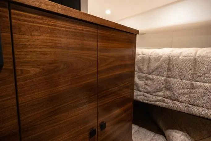 Boujie Yacht Photos Pics Interior of 2025 Viking 82 Convertible yacht with wooden cabinet and cozy bedding.