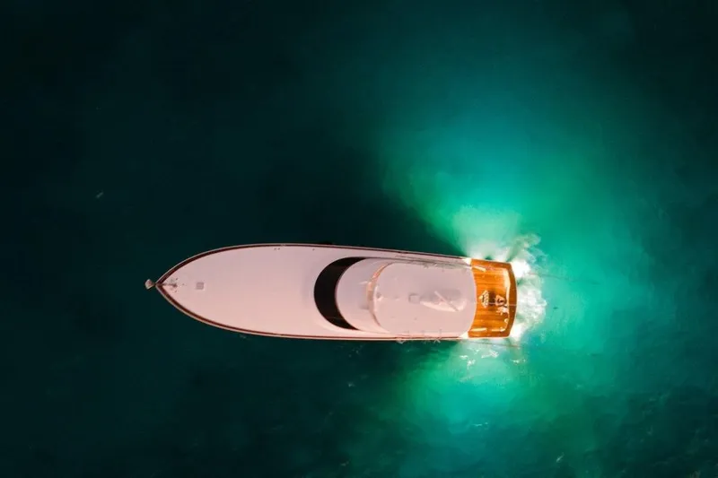 Boujie Yacht Photos Pics Aerial view of 2025 Viking 82 Convertible yacht cruising in illuminated turquoise waters.