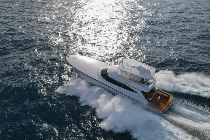 Boujie Yacht Photos Pics 2025 Viking 82 Convertible yacht cruising on open sea, creating waves.