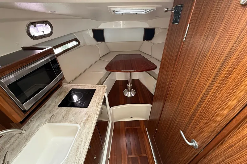  Yacht Photos Pics 2017 Pursuit OS 325 Offshore cabin interior with kitchenette and seating area.