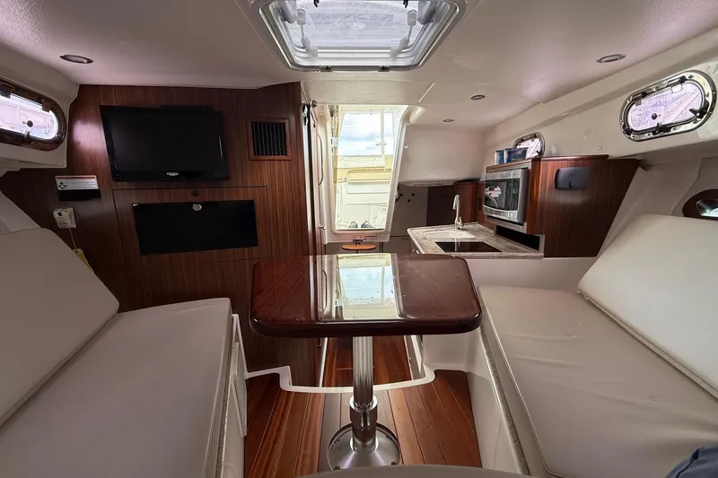  Yacht Photos Pics Interior of 2017 Pursuit OS 325 Offshore boat with seating, table, and kitchenette.